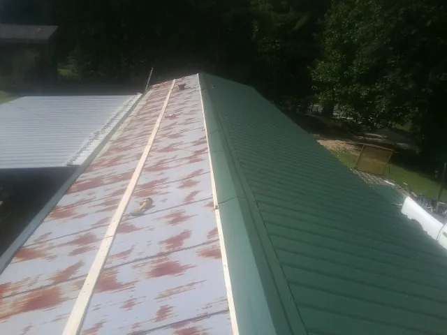 Old rusted panels beside newly installed green metal roofing — Wind Damage Roof Repair by Roofing Brothers in Ypsilanti