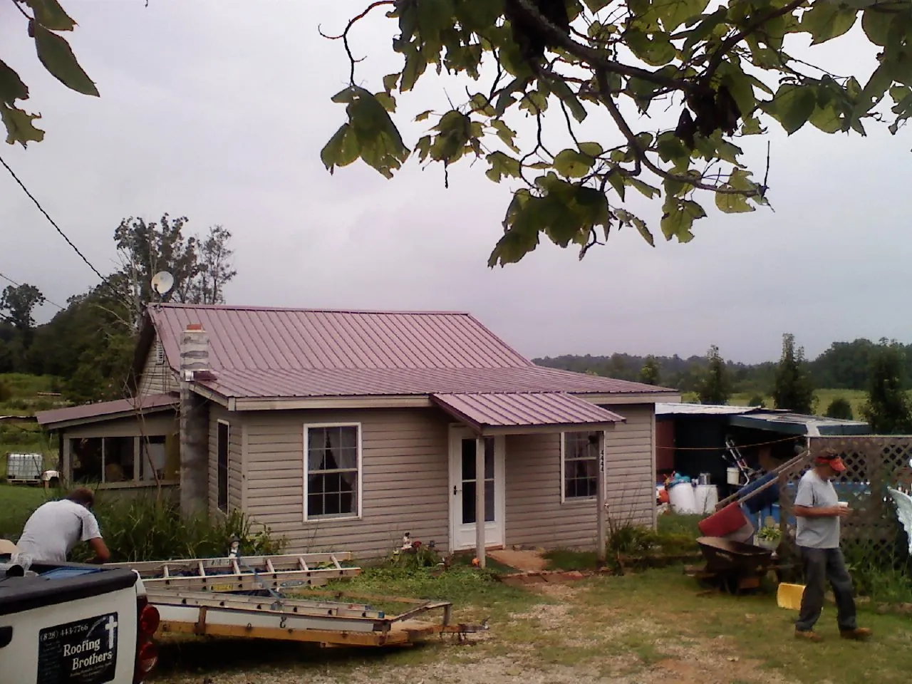 Crew finishing a mauve metal roof on a small farmhouse in Ypsilanti